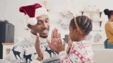 Yumuşak kanepede otururken küçük kızıyla oynayan Afrikalı Amerikalı babayla ilgilenmek. Noel ağacına bakan çocuklu güzel bir anne. Arkadaşça bir aile evde vakit geçirir..