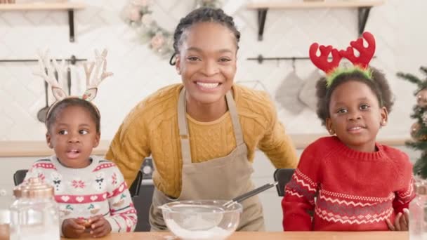 美丽的非洲裔美国母亲和她的小孩准备在厨房里烹调美味的食物 可爱的孩子们戴着带圣诞装饰品的头巾 快乐的家庭观念 — 图库视频影像