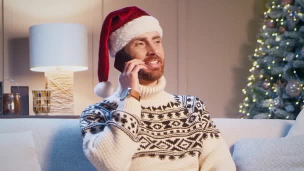 Красивый Белый Мужчина Шляпе Санта Клауса Разговаривая Телефону Уютной Комнате — стоковое видео