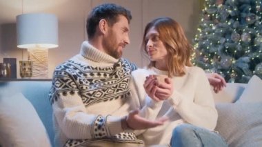 Güzel, beyaz, evli bir çift modern odada Noel ağacıyla koltukta otururken iletişim kuruyor. Sevgili karısının Noel arifesinde romantik bir akşam veya iki kez saçını okşayan şefkatli bir adam.