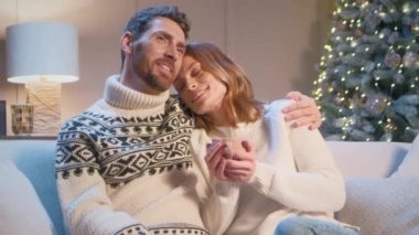 Kafkasyalı çiftin Noel ağacıyla sıcak oturma odasında romantik bir akşam geçirmesini seviyorum. Çekici bir adam güzel karısına bir fincan sıcak çayla sarılıyor. Noel arifesinde birlikte vakit geçirmek..