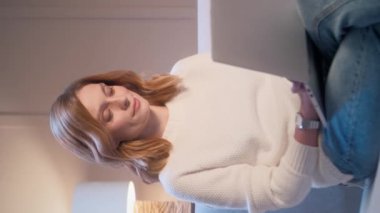 Kafkasyalı bir kadının rahat bir koltukta otururken dizüstü bilgisayarında yazı yazarken dikey görüntüsü. Evde vakit geçirirken teknoloji aletini kullanan güzel bir kadın. Evde boş vakit geçirmek..