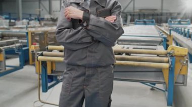 Fabrikada üretim makinesinin önünde duran sevimli beyaz kadın. Kameraya gülümserken gri üniforma ve kask giyiyordu. Genç bir bayanın iş saatlerinde iyi hisleri var..