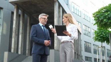 Sokakta başarılı bir iş adamı ya da siyasetle röportaj yaparken elinde mikrofon olan güzel beyaz bir kadın. İnsanlar birbirleriyle kamera önünde konuşuyorlar. Kayıt haberleri.