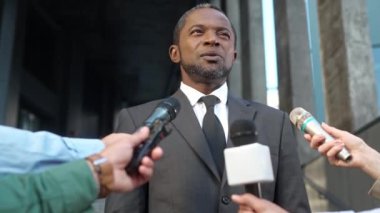 Afrikalı Amerikalı politikacı ya da girişimci basın toplantısında konuşma yapıyor. Gazetecilerin sorularına cevap veren siyah şık kostümlü zeki bir adam. Halka açık. TV medyası.