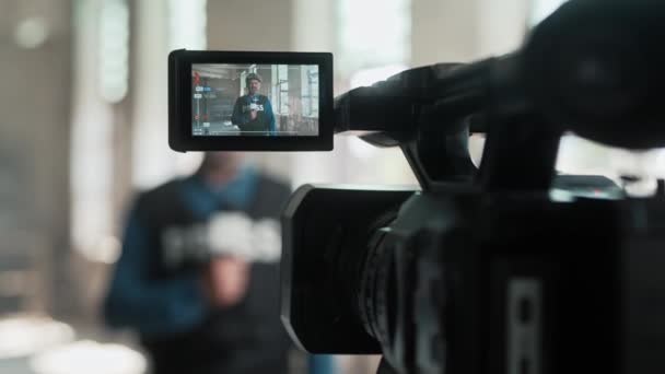 在废弃的建筑里用麦克风交谈的军事记者的相机照片 男子穿着防弹背心和防护设备在直播新闻 战争概念 — 图库视频影像