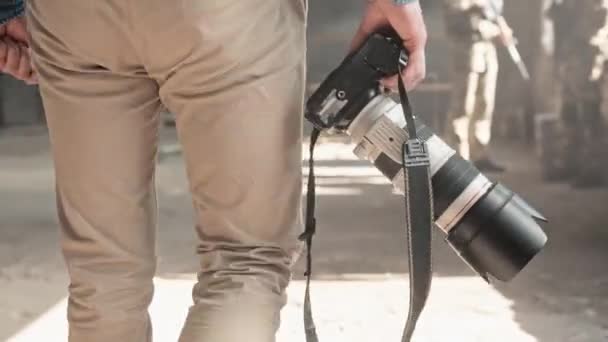 放棄された建物に立っている兵士に向かって歩く写真カメラの男のカメラビュー 戦争地帯で働くレポーター 戦争特派員がニュースを報道する フォトジャーナリズム — ストック動画