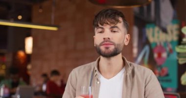 Kafede oturup yemek çiğneyen ve taze meyve suyu içen çekici bir adamın portresi. Barda lezzetli yemekler yerken iyi hissetmek. Yakışıklı erkek kafeteryada eğleniyor..