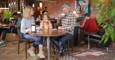 Kafeteryada ya da pizzacıda harika bir hafta sonu geçiren tatmin olmuş Kafkas ailesine zum yapıyorum. Önemseyen ebeveynler kızlarıyla iletişim kurup yemeklerini bekliyorlar. Evde dinlenirken birlikte gülümsüyoruz..