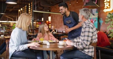 Restoranda müşterilere hizmet eden çok ırklı genç bir garson. Mutlu aileyle iletişim kuran ve onlardan emir alan çekici bir işçi. Mutlu aile, kafede lezzetli yemekler ve akşam yemeği yiyor..