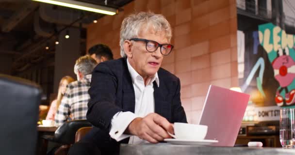 노트북에서 일하는 성숙한 코카서스 소유자 커피를 마시는 바에서 시간을 보내는 — 비디오