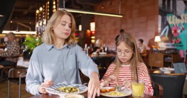 Güzel bir anne ve küçük çocuğu kafede yemek yiyorlar. Kafkas ailesi lezzetli yemeklerle masada oturuyor ve lokantada yemek yerken iletişim kuruyorlar. Beslenme kavramı.