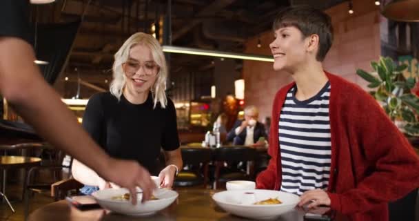 服务员在咖啡店招待两个漂亮的白人妇女 正接受美味食物的女性 坐在餐桌边 一边吃着菜 一边开心地微笑着 在当地酒吧举行的友好会议 — 图库视频影像