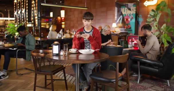 Kafkasyalı Gözlüklü Kadını Akıllı Telefonuyla Zumlarken Masada Lezzetli Yemek Içeceklerle — Stok video