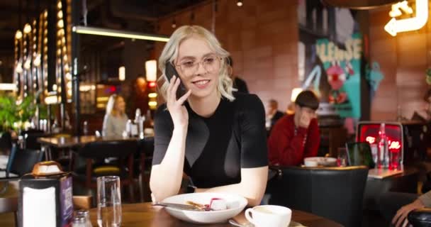 Młoda Biała Kobieta Blond Włosami Rozmawiająca Przez Telefon Przyjaciółką Kawiarni — Wideo stockowe
