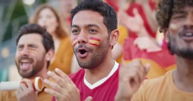 Bir grup çok ırklı arkadaş İspanya milli takımı için stadyum tribünlerine tezahürat yapıyor. Favori takımı desteklemek için spor müsabakalarına bağırıp çağırıyorlar. Yüzlerde İspanyol bayrakları.