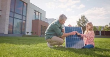 Baba ve kızı gezegen ekosistemini korumanın önemini açıklıyorlar. Baba ve kızı güneş panelinin yanında çömeldiler. Dışarıda çimenlikte bir adam ve kız var. Güneş ışığının elektriğe dönüştürülmesi.