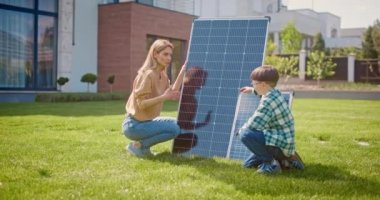 Anne ve oğul gezegenlerin ekosistemini korumanın önemini konuşuyor. Anne ve oğlu güneş panellerinin yanında. Kadın ve çocuk evin arka bahçesinde çimenlikte. Güneş ışığının elektriğe dönüştürülmesi.