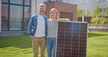 Güneş panelinin yanında duran mutlu evli çift. Alternatif enerji kaynağıyla gülümseyen kadın ve erkek. Çimlerde güneş paneli olan kadın ve erkek. Güneş enerjisinin elektriğe dönüştürülmesi.