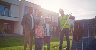 Afrikalı Amerikalı mühendis dört kişilik aileyle konuşuyor. Erkek müteahhit güneş panelini tutuyor. Aile, sunak kaynaklı enerji kullanmayı planlıyor. Çevre bilinci kavramı. Yenilenebilir enerji sistemi.