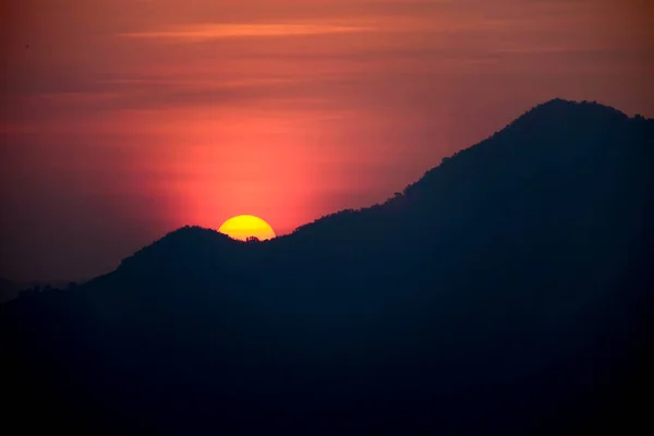 The sun rises behind the mountain at morning background image