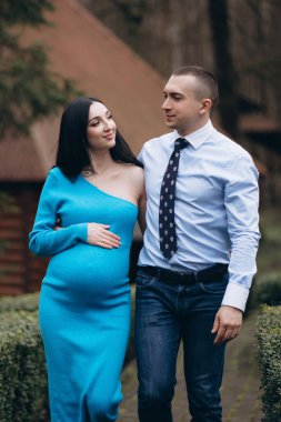 pregnant woman with her husband walking together in the park. married couple