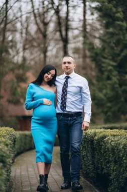 pregnant woman with her husband walking together in the park. married couple