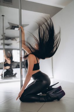 Genç seksi, zayıf esmer, direğin üzerinde dans ediyor, saçlarını sallıyor. Arkaplan yansıması