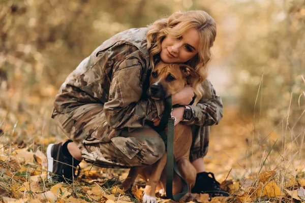 A woman soldier hugs her dog.