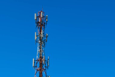 Mavi bulutlu arka planı olan cep telefonu anten kulesi. mavi gökyüzü arkaplanlı yüksek voltaj kulesi.