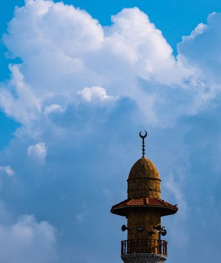 Bulutlu gökyüzünün arka planında caminin minaresi.