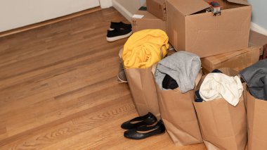 Giysili karton kutular, yerde ayakkabılar taşınmak için eşyalar, taşınma günü ve fotokopi alanı ile taşınma konsepti.