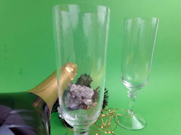 New Year a Green And Golden Glass Bottle Of Sparkling Wine with glasses, goblets. Festive New Year Greeting Cards, with little lights.