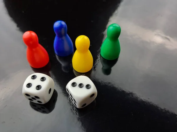 Board Game Pawns And Dice With Colored Pieces. Reflections film black color.