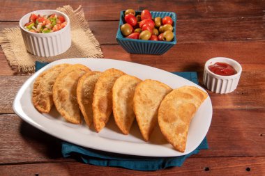 Kızarmış hamur işleri, Pastel Frito Brasileiro, ahşap masada. Pastel de carne.