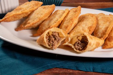 Kızarmış hamur işleri, Pastel Frito Brasileiro, ahşap masada. Pastel de carne.