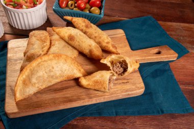 Kızarmış hamur işleri, Pastel Frito Brasileiro, ahşap masada. Pastel de carne.