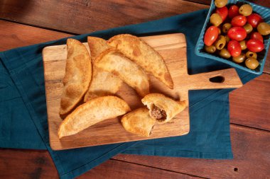 Kızarmış hamur işleri, Pastel Frito Brasileiro, ahşap masada. Pastel de carne.