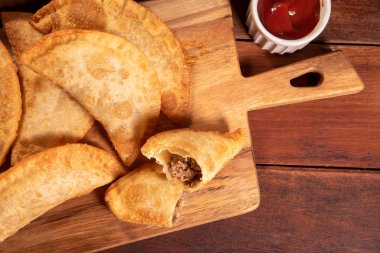 Kızarmış hamur işleri, Pastel Frito Brasileiro, ahşap masada. Pastel de carne.