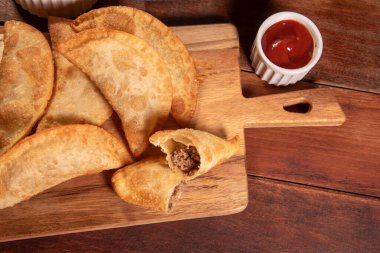 Kızarmış hamur işleri, Pastel Frito Brasileiro, ahşap masada. Pastel de carne.