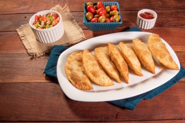 Kızarmış hamur işleri, Pastel Frito Brasileiro, ahşap masada. Pastel de carne.