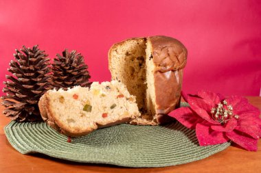 Yeşil kurdeleli Panettone ve kırmızı Noel arka planı ve ahşap masa..