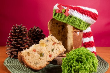 Panettone, Noel Baba şapkalı ahşap masa ve kırmızı arka plan.