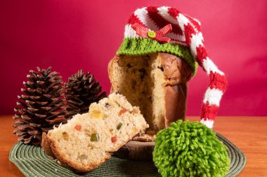 Panettone, Noel Baba şapkalı ahşap masa ve kırmızı arka plan.