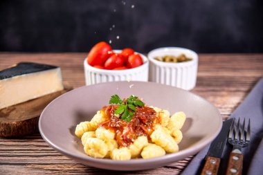 Ahşap bir masanın üzerinde rendelenmiş parmesan peynirli Gnocchi.