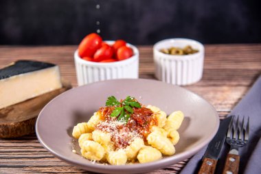 Ahşap bir masanın üzerinde rendelenmiş parmesan peynirli Gnocchi.