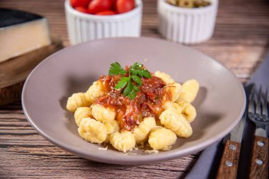 Ahşap bir masanın üzerinde rendelenmiş parmesan peynirli Gnocchi.