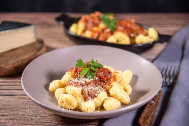 Ahşap bir masanın üzerinde rendelenmiş parmesan peynirli Gnocchi.