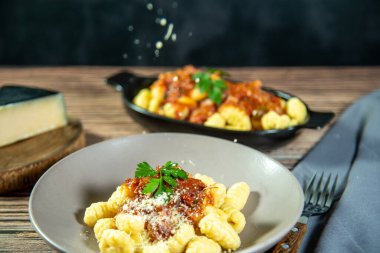 Ahşap bir masanın üzerinde rendelenmiş parmesan peynirli Gnocchi.