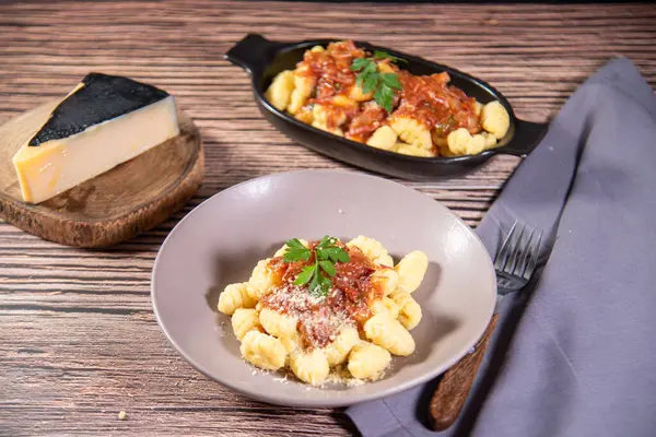 Ahşap bir masanın üzerinde rendelenmiş parmesan peynirli Gnocchi.